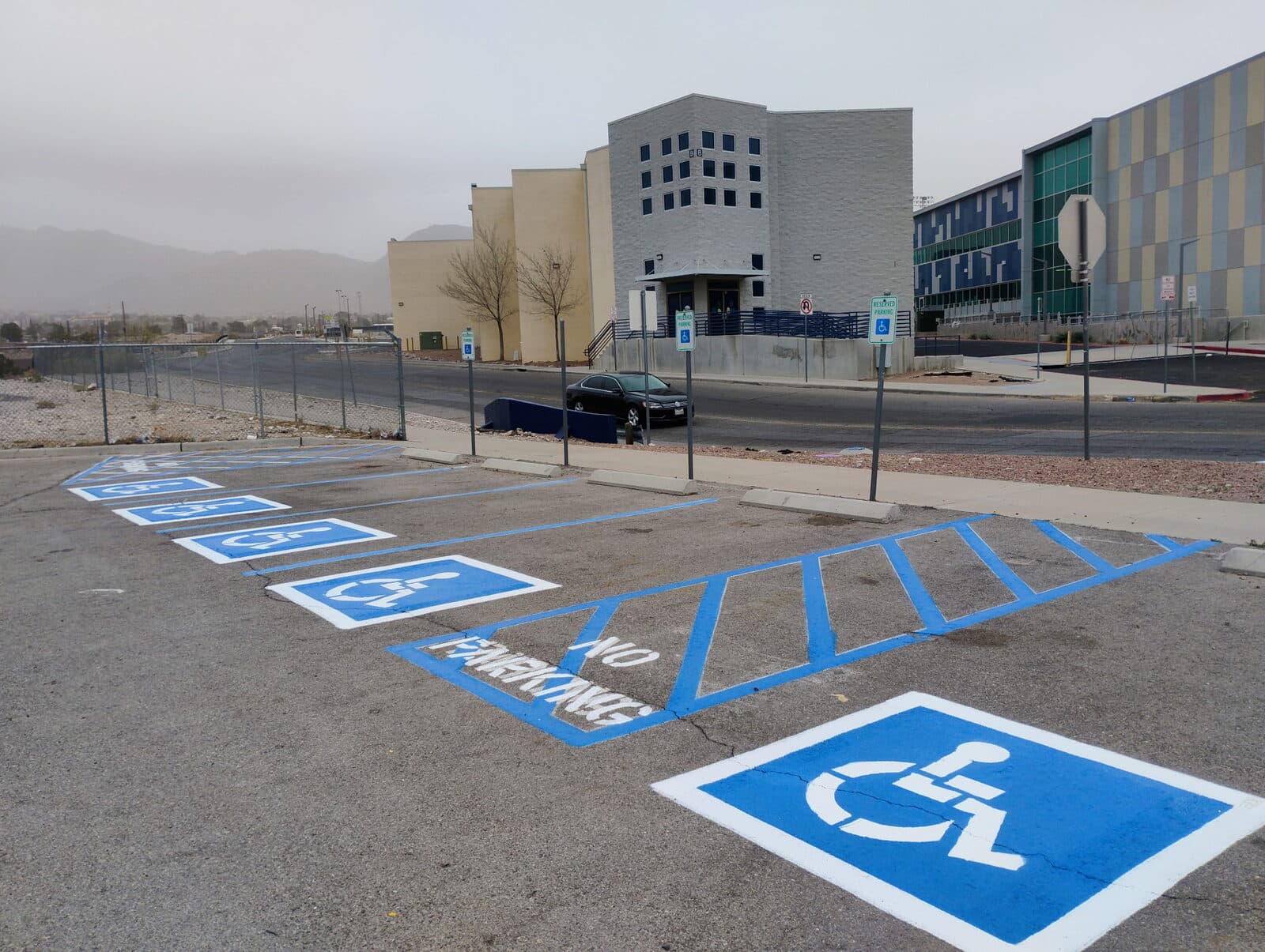 Fresh blue ADA stalls and stencils painted on a campus parking lot