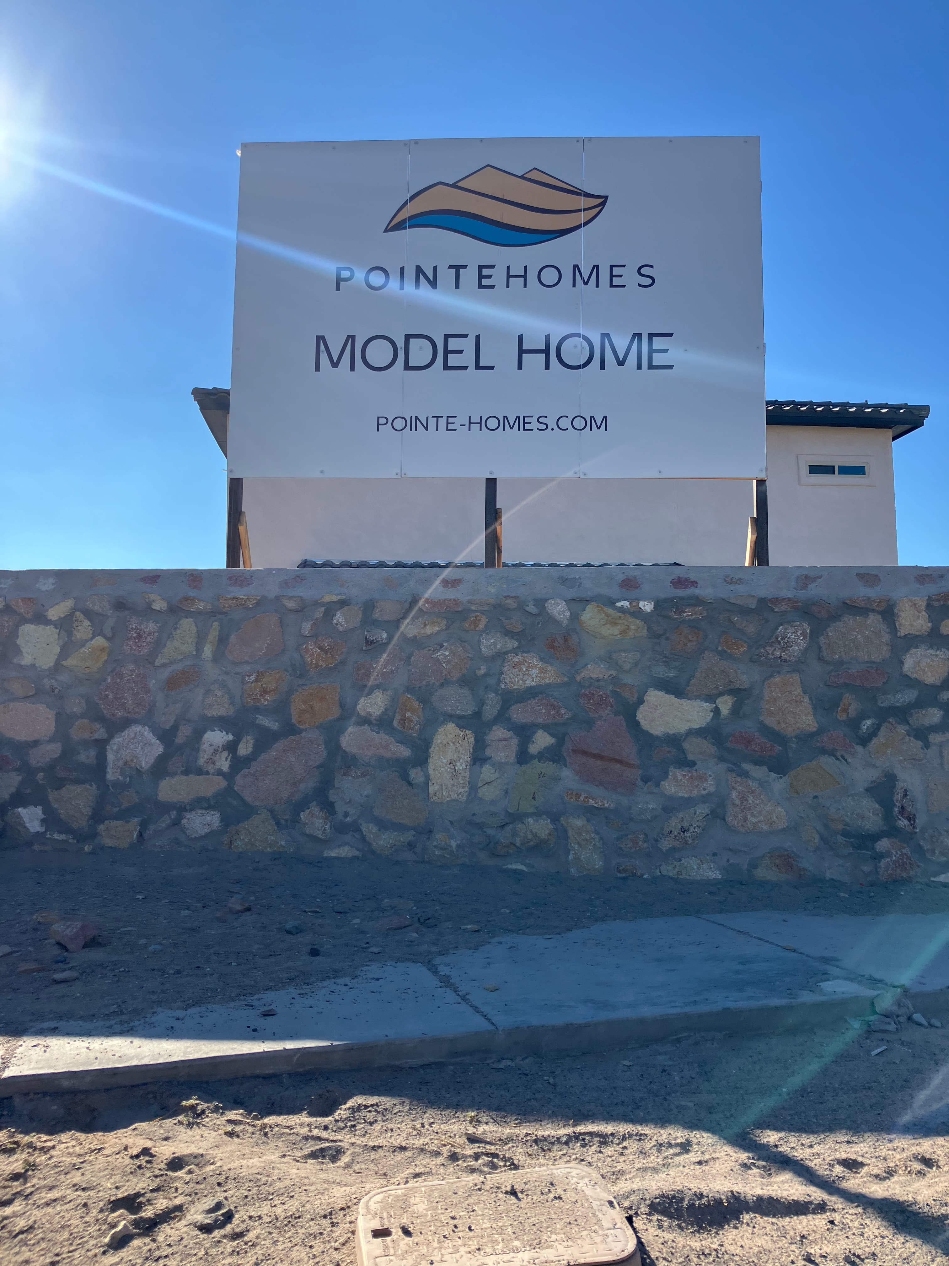 Pointe Homes model home panel standing over a stone community wall